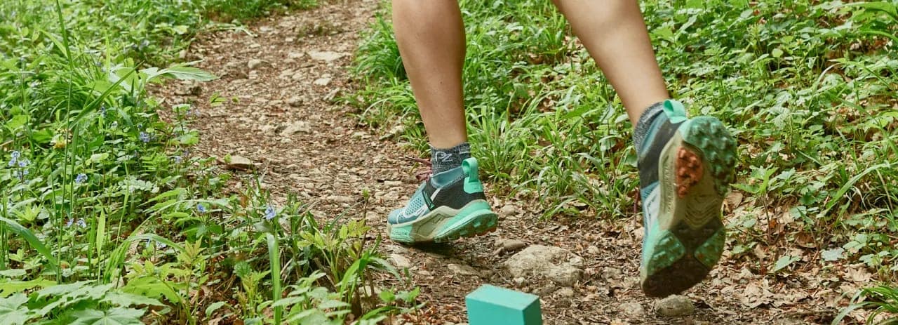 Laufschuhe auf einem Waldweg, am Wegrand ein Markierungsklotz